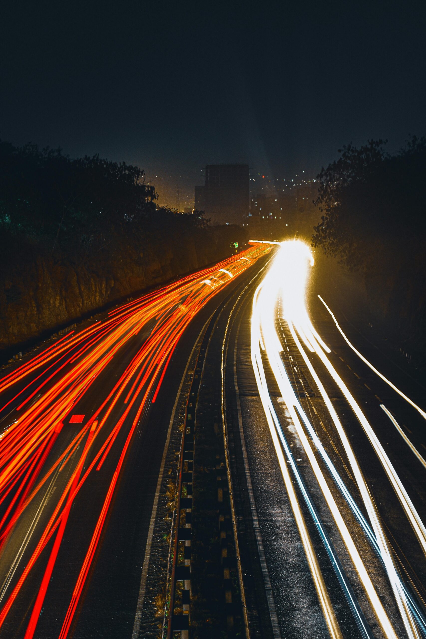 A dynamic long exposure shot capturing the vibrant light trails on a city highway at night.
